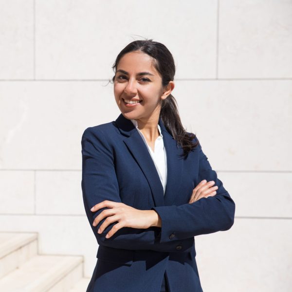 Confident ambitious young professional smiling an camera. Portrait of young woman with arms crossed wearing formal suit and posing on outdoor stairs. Young businesswoman concept